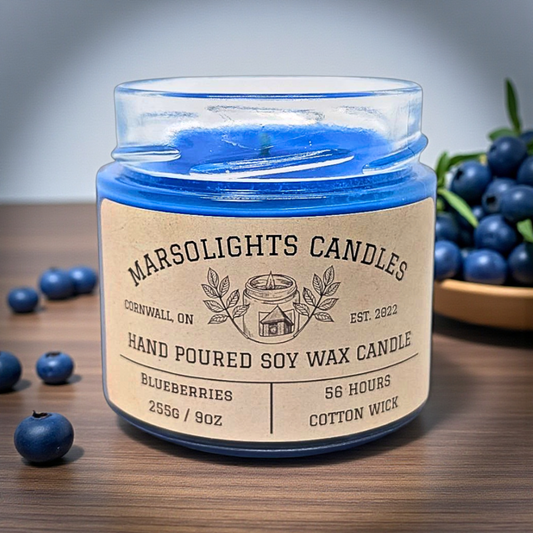 Blue candle in a glass jar with a label on a wooden surface surrounded by blueberries.

Label reads 56 hours for burn time
Wick is cotton 
Size if 255 grams or 9 oz
Blueberries Aroma Soy Scent Candle
by Marsolights Candles -Cornwall Ontario