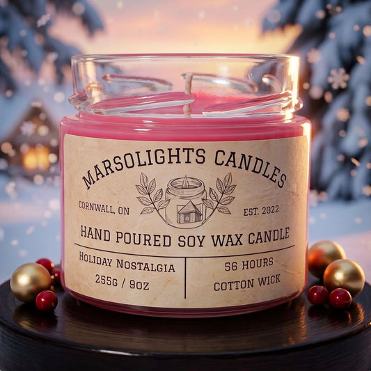 Holiday Nostalgia Soy Candle displayed with festive holiday décor. The candle features juicy pomegranate, sweet blackberry, fresh evergreen boughs and rich mahogany notes. 9 ounce or 255 grams, 56-hour burn time, cotton wick, soy candle, made in Canada, paraben free.