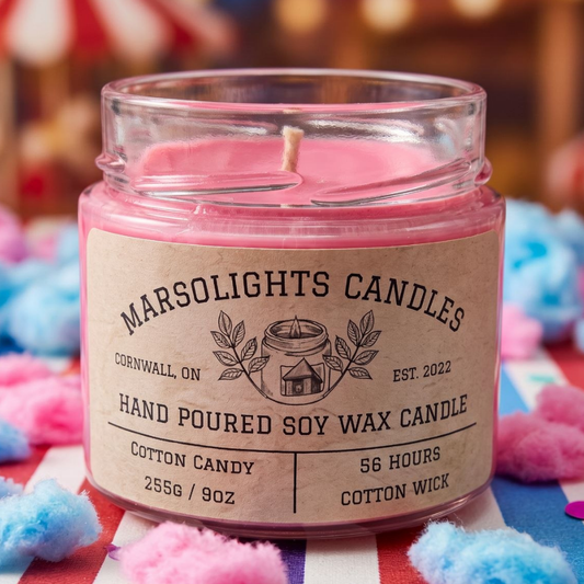 Cotton Candy Soy Candle displayed with colourful summer fair-inspired décor. The candle features spun sugar, pink berries, sparkling citrus, candied strawberry, caramelized vanilla, creamy musk and sugar crystals. 9 ounce or 255 grams, 56-hour burn time, cotton wick, soy candle, made in Canada, paraben free.