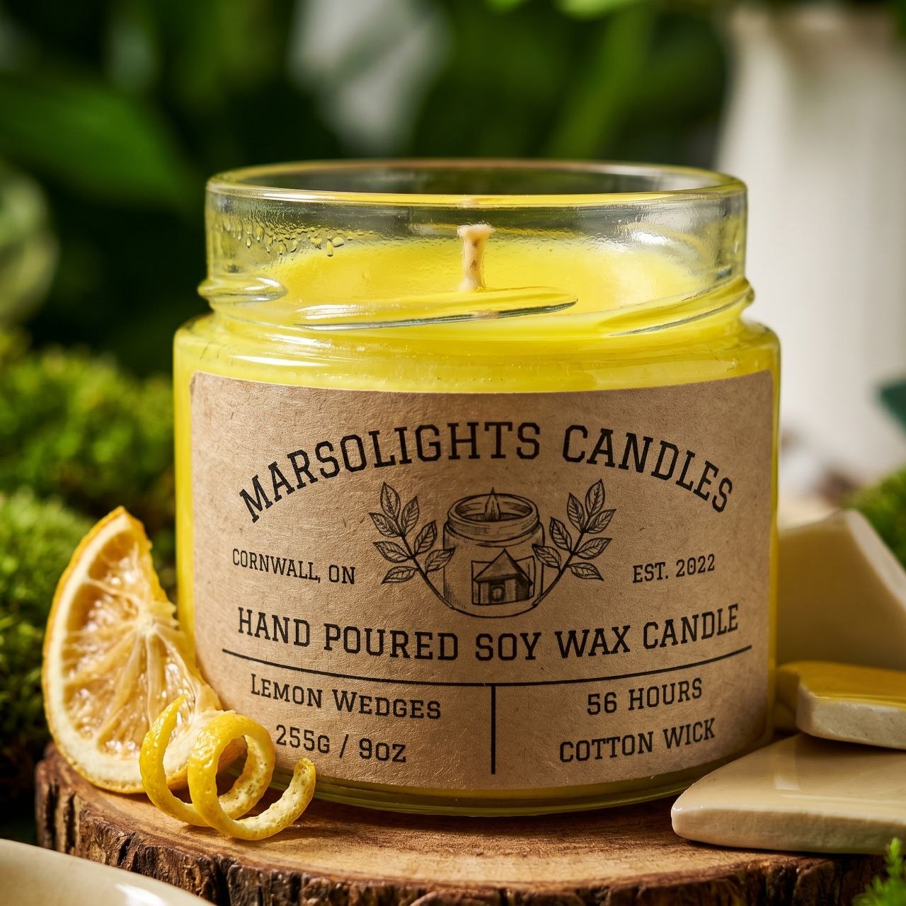 A Candle on a stump podium with lemon wedges and zest.
Scent: A Fusion of scents such as lemon, lemongrass, grapefruit, orange, lime, and florals that leaves a citrus medley that instantly energizes. 
Produced: Made in Canada.
Size: 9 ounces or 255 grams
Burn time: 56 Estimated Hours
Wick type: Cotton
Scent: Lemon Wedges