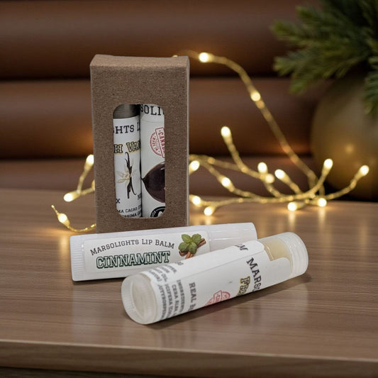 Two lip balm tubes with packaging on a wooden surface with decorative lights in the background. Build your perfect duo with our 2-Pack Choose Your Flavour Lip Balm. Made in Canada with your choice of flavours and crafted using premium hydrating ingredients, these balms deliver lasting moisture and a smooth, comfortable finish.

Each balm is made with mango butter or cocoa butter, plus high-grade beeswax, avocado oil, coconut oil, olive oil, and shea butter to deeply nourish and lock in hydration.